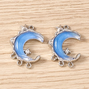 Close-up of blue crescent moon pendants with white rhinestones for DIY jewelry making