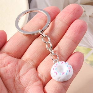 Detailed view of white donut charm with colorful sprinkles held by hand on key ring