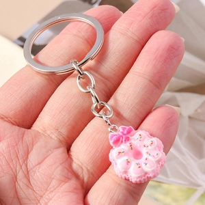 Detail of pink donut keychain with bow and sprinkles held in hand for scale
