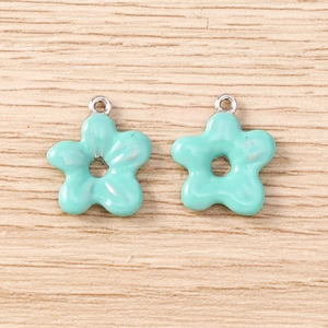 Macro shot of mint green enamel flower pendants on wood for DIY jewelry making