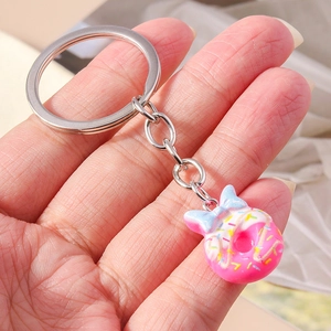 Detail of pink donut keychain with colorful sprinkles and a blue gradient bow charm