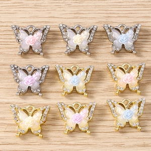 Macro detail of rhinestone butterfly pendants with resin roses for jewelry making