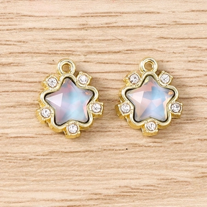 Détail de pendentifs étoile dorée avec pierre centrale irisée et petits strass transparents