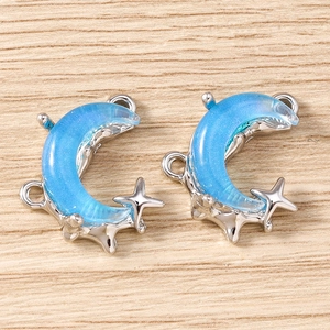 Detailed shot of two silver moon pendants with blue resin and tiny star charms for jewelry