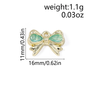 Dettaglio macro del ciondolo a fiocco dorato con pietre verdi e misure 16mm x 11mm