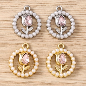 Detail of tulip flower charms with pink rhinestones and pearls on wood background