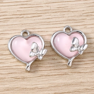 Gros plan de pendentifs cœur rose avec détails de nœud et métal argenté pour bijoux DIY