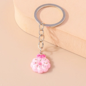 Close-up of pink donut keychain with sprinkles and bow on a geometric stand