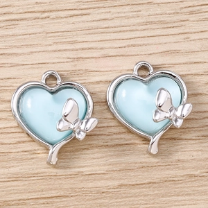Vue détaillée de breloques cœur bleu avec papillon argenté pour la création de bijoux