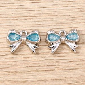 Dettaglio di ciondoli a fiocco in argento con pietre azzurre su sfondo in legno
