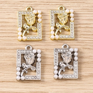 Detail of rose relief pendants with rhinestones and pearls on a wooden surface