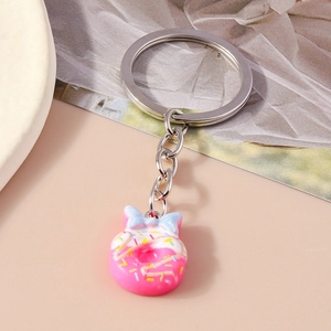Detailed view of pink donut keychain with blue bow on soft beige background texture