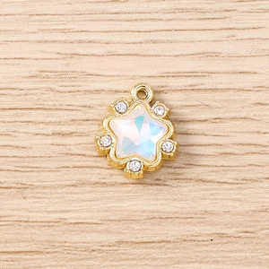 Détail macro du pendentif étoile avec gemme irisée et strass sur fond de bois clair