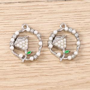 Detailed macro view of two silver floral pendants with pearls, rhinestones, and green enamel