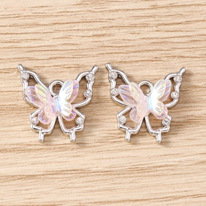 Detail of rhinestone butterfly charms with iridescent wings on light wood background