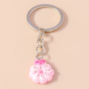 Macro detail of pink donut keychain with white frosting, sprinkles, and pink bow