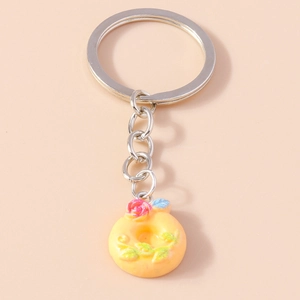 Detailed macro of a yellow donut keychain with pink rose and silver metal chain