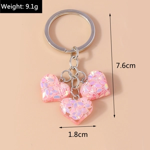 Vue détaillée des breloques cœur rose translucide avec paillettes sur un porte-clés argenté