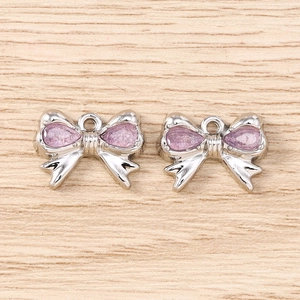 Dettaglio di ciondoli a fiocco argento con cristalli viola per gioielli fai-da-te