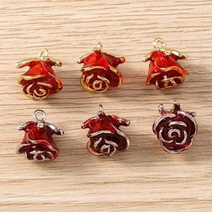 Detailed close-up of red enamel rose charms with gold and silver metal bases for jewelry