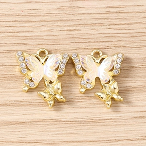 Detailed close-up of golden butterfly charms with rhinestones on light wood background