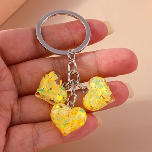 Détail de trois pendentifs en résine en forme de cœur avec paillettes sur porte-clés argenté