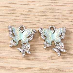 Macro detail of rhinestone butterfly pendants with iridescent green inlay on wood surface