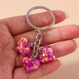 Détail de trois pendentifs en résine en forme de cœur avec paillettes violettes sur porte-clés