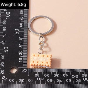 Detail shot of biscuit-shaped keychain showing dimensions and scale on a beige surface