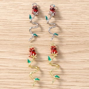 DIY rose flower pendants with red enamel petals and gold silver stems on wooden surface