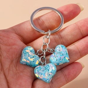 Détail de trois pendentifs en cœur à paillettes bleu clair sur un porte-clés argenté