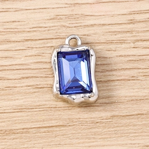 Primer plano de un colgante de strass azul oscuro rectangular con marco de metal plateado