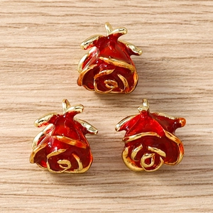 Detailed macro view of three red enamel rose flower pendants with gold plated edges