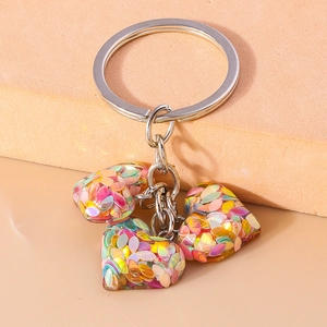 Détails de trois breloques en forme de cœur avec des paillettes irisées colorées