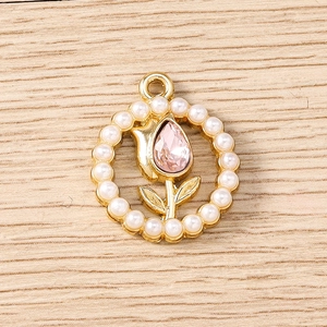 Macro shot of gold floral charm with pearl border and pink tulip zircon detail