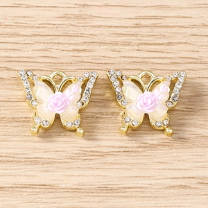 Macro shot of gold-plated butterfly charms with rhinestones and pink resin rose flower for DIY