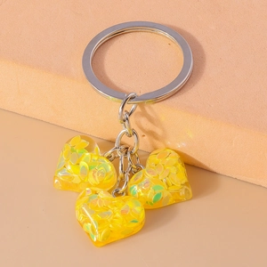 Gros plan de trois pendentifs cœur en résine jaune avec paillettes et anneau argent