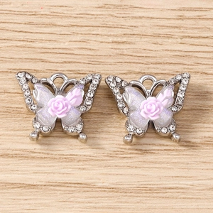 Detailed macro of two butterfly charms with pink roses and sparkly rhinestones for DIY jewelry