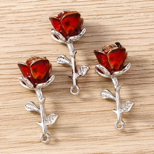 Macro detail of three 3D rose flower pendants with deep red petals and silver metal stems