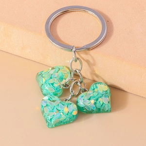 Détail du porte-clés argenté avec trois breloques cœurs à paillettes vert menthe