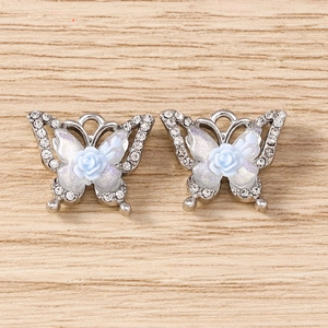 Detail of butterfly pendants with rhinestones, resin wings, and a blue rose accent