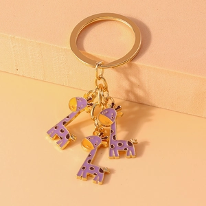 Gros plan d'un porte-clés doré avec trois adorables pendentifs girafe en émail violet