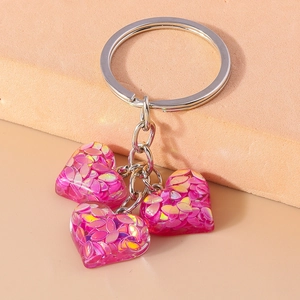 Vue détaillée des pendentifs cœur en résine rose avec paillettes et porte-clés en métal