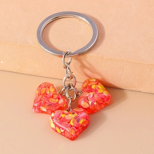 Gros plan de pendentifs en forme de cœur avec paillettes et porte-clés en métal argenté