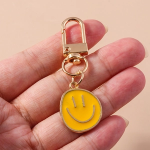Détail d'un porte-clés sourire jaune en métal avec fermoir mousqueton doré poli