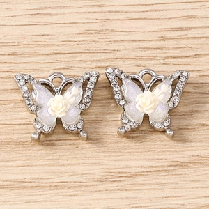 Macro detail of rhinestone butterfly pendant with cream rose and silver hanging loop