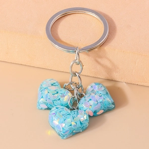 Détail du porte-clés argenté avec trois charms en forme de cœur à paillettes bleues