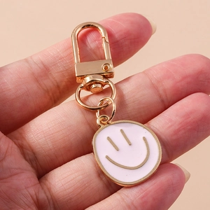 Détail du porte-clés visage souriant rose avec fermoir doré et pendentif en émail