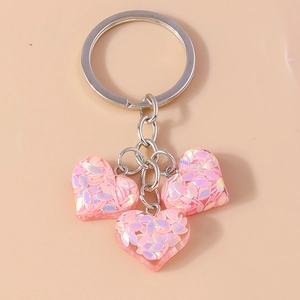 Détail de breloques en cœur rose translucide avec paillettes sur un porte-clés argenté