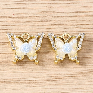 Macro view of gold butterfly pendants with rhinestones and blue resin roses